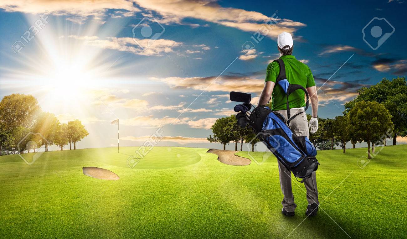 Golf Player in a green shirt walking with a bag of golf clubs on his back, on a golf course. - 53264250 Golf Player in a green shirt walking with a bag of golf clubs on his back, on a golf course. - 53264250