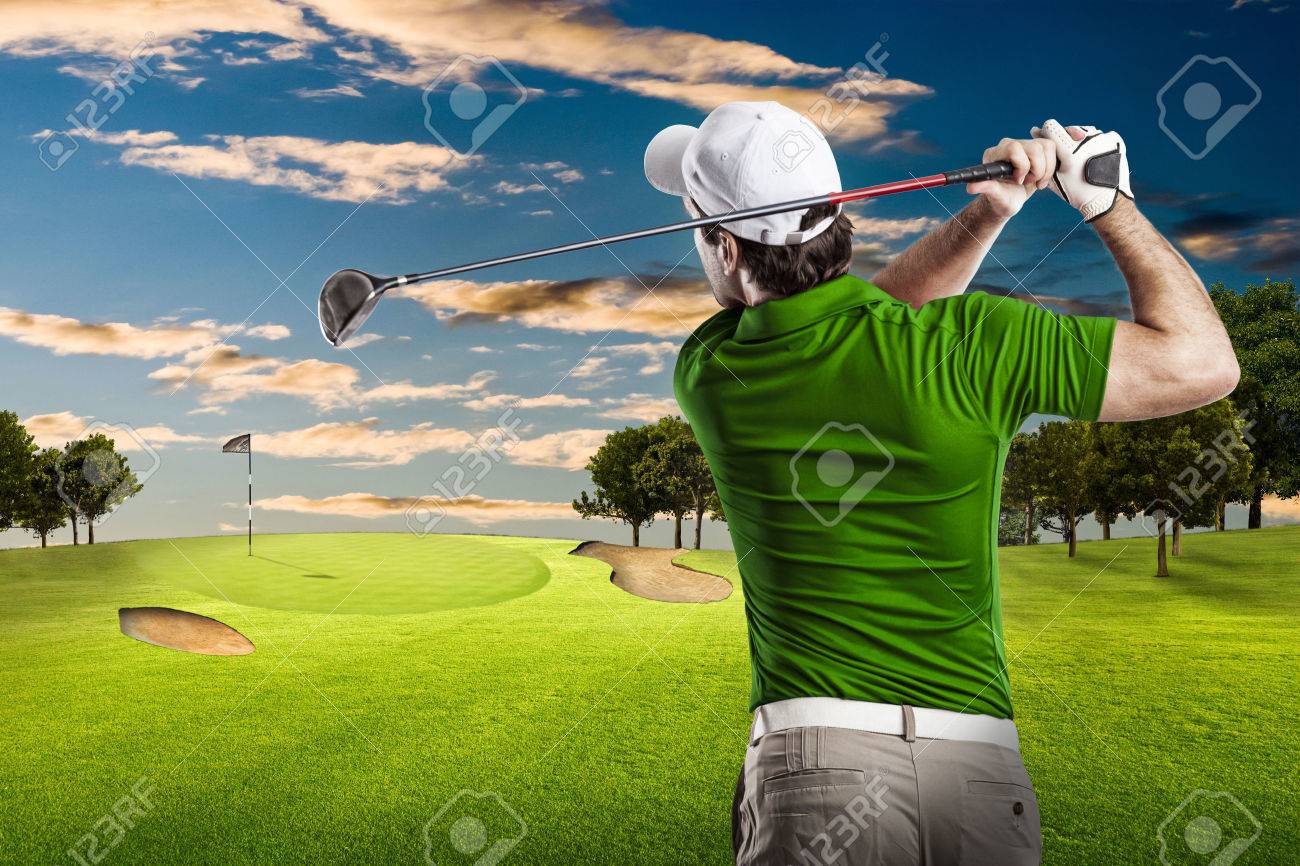 Golf Player in a green shirt taking a swing, on a golf course. - 53264410 Golf Player in a green shirt taking a swing, on a golf course. - 53264410