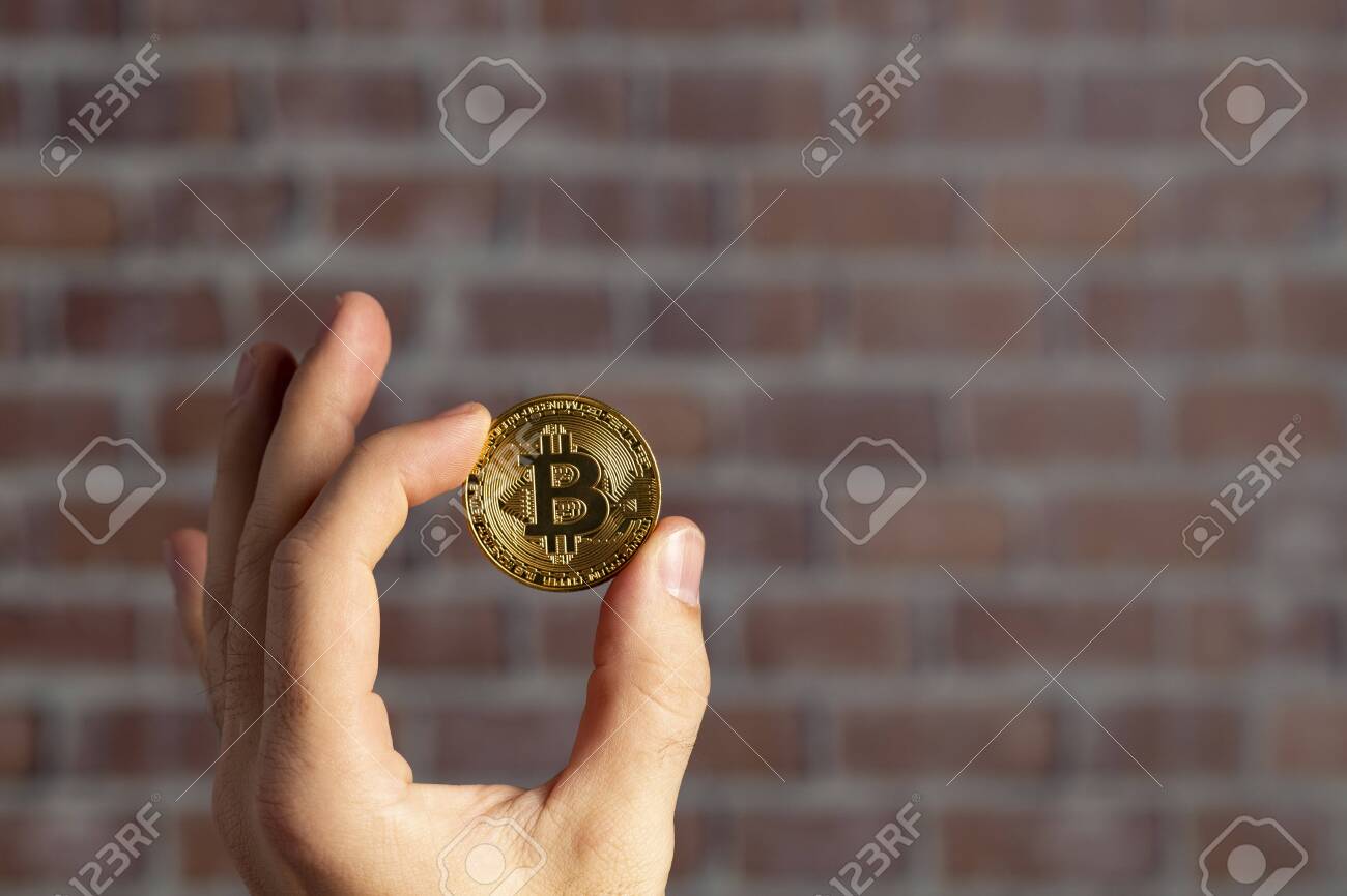 벽돌 벽 앞에서 실제 비트코인을 들고 있는 남자 손 로열티 무료 사진, 그림, 이미지 그리고 스톡포토그래피. Image 129311356