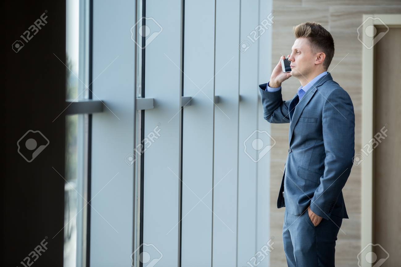 De Rubia La El Por Hombre Oscuro Negocios Hablando Un Teléfono Traje En Mirando Ventana Foto Archivo wdI4xqBw