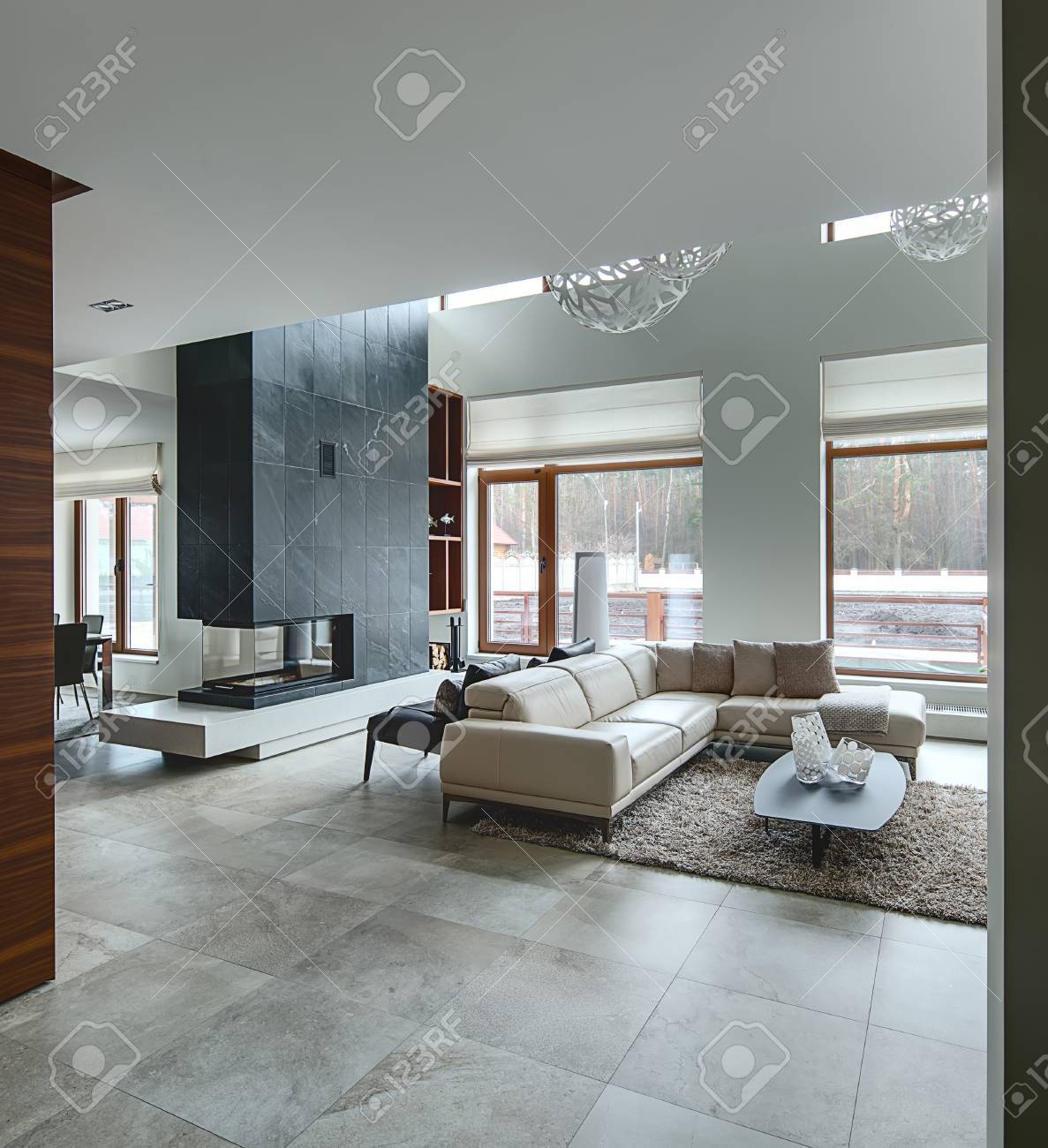 光の壁と大きな白のモダンな様式のホールはラウンド上部に装飾的なランプです 右側に枕格子縞ベージュ ソファ 3 つの装飾的なつぼ ソファの後ろに枕を 2 つ黒いアームチェアーとダークウッドのテーブルがあります それらがの下で の写真素材 画像素材 Image