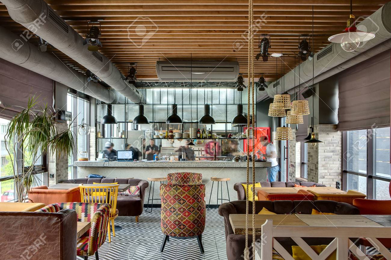 Interior Fantastico En Un Estilo Loft En Un Restaurante Mexicano Con Cocina Abierta En El Fondo En Frente De La Cocina Hay Mesas De Madera Con Sillas Y Sofas Multicolores En Los
