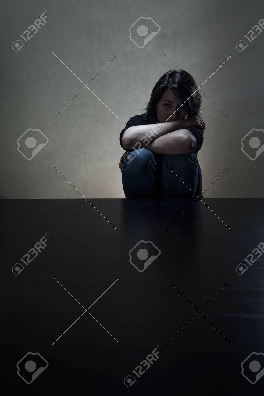 sad girl sitting alone in dark room vertical stock photo picture