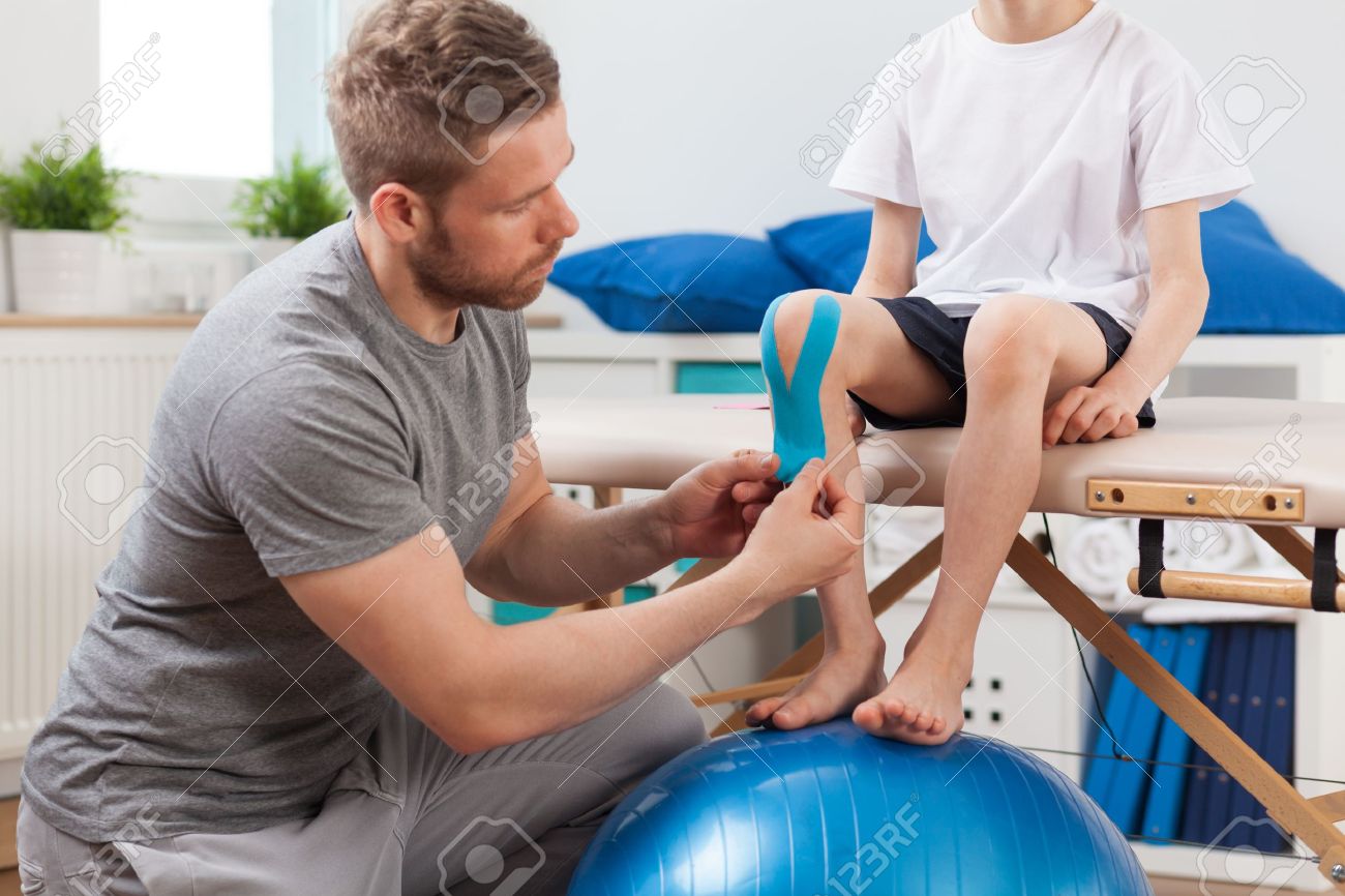 Physical therapist applying young patient medical tape - 42429336 Physical therapist applying young patient medical tape - 42429336