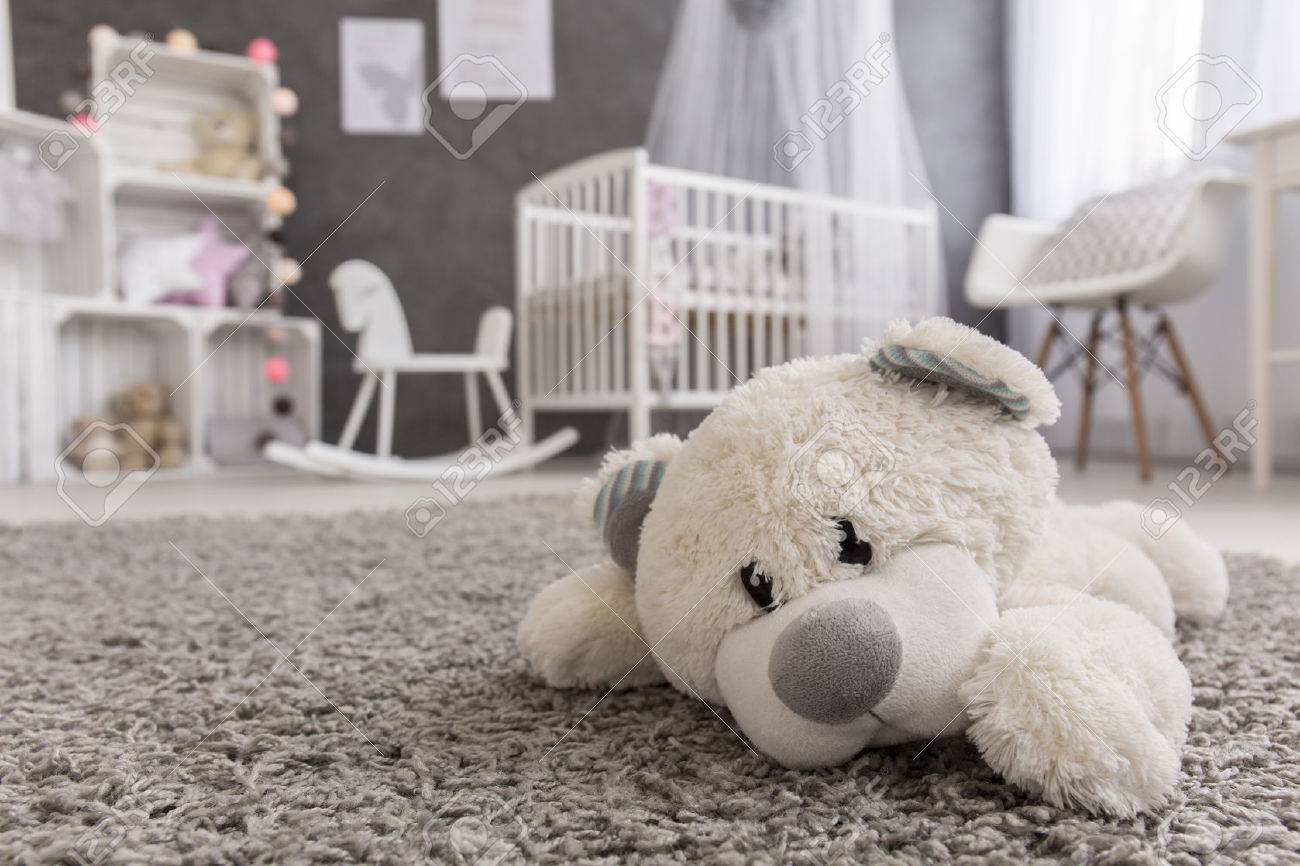 Shot of a teddy bear laying on a carpet in a cozy baby girl room - 57978918 Shot of a teddy bear laying on a carpet in a cozy baby girl room - 57978918