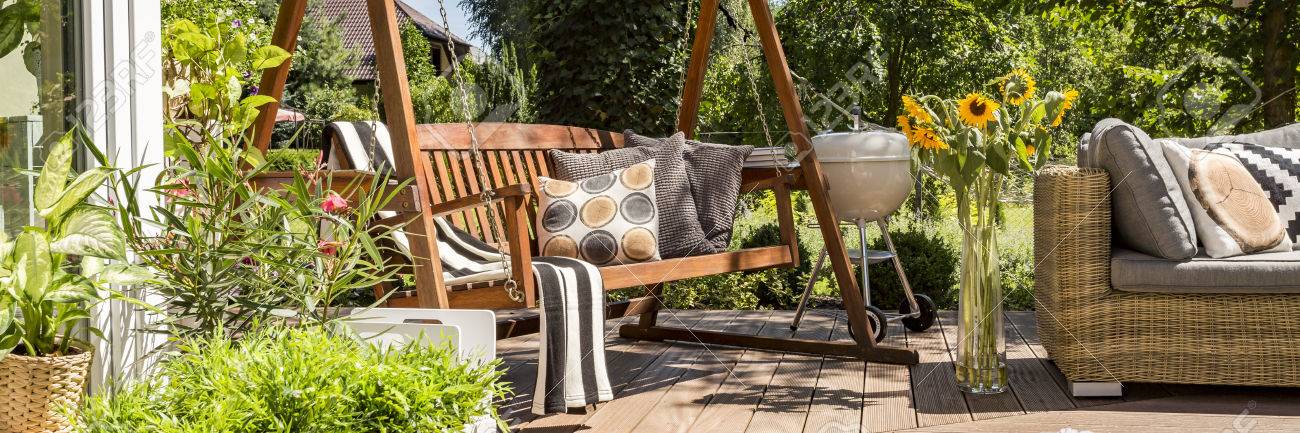 Cozy house terrace with wooden garden swing and a grill - 62746804 Cozy house terrace with wooden garden swing and a grill - 62746804