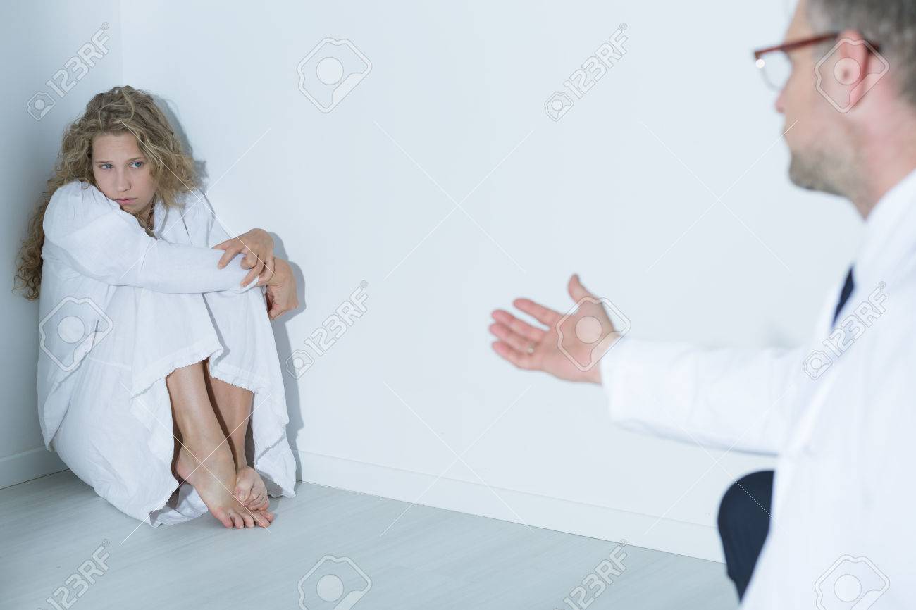 白い部屋の隅に座っている彼の患者に話している精神科医のショット の写真素材 画像素材 Image