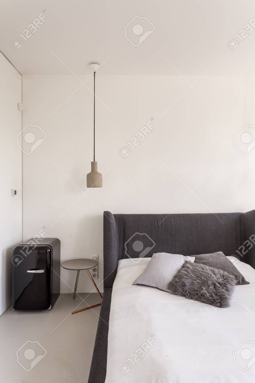 White Bedroom With Dark Grey Bed And Compact Fridge