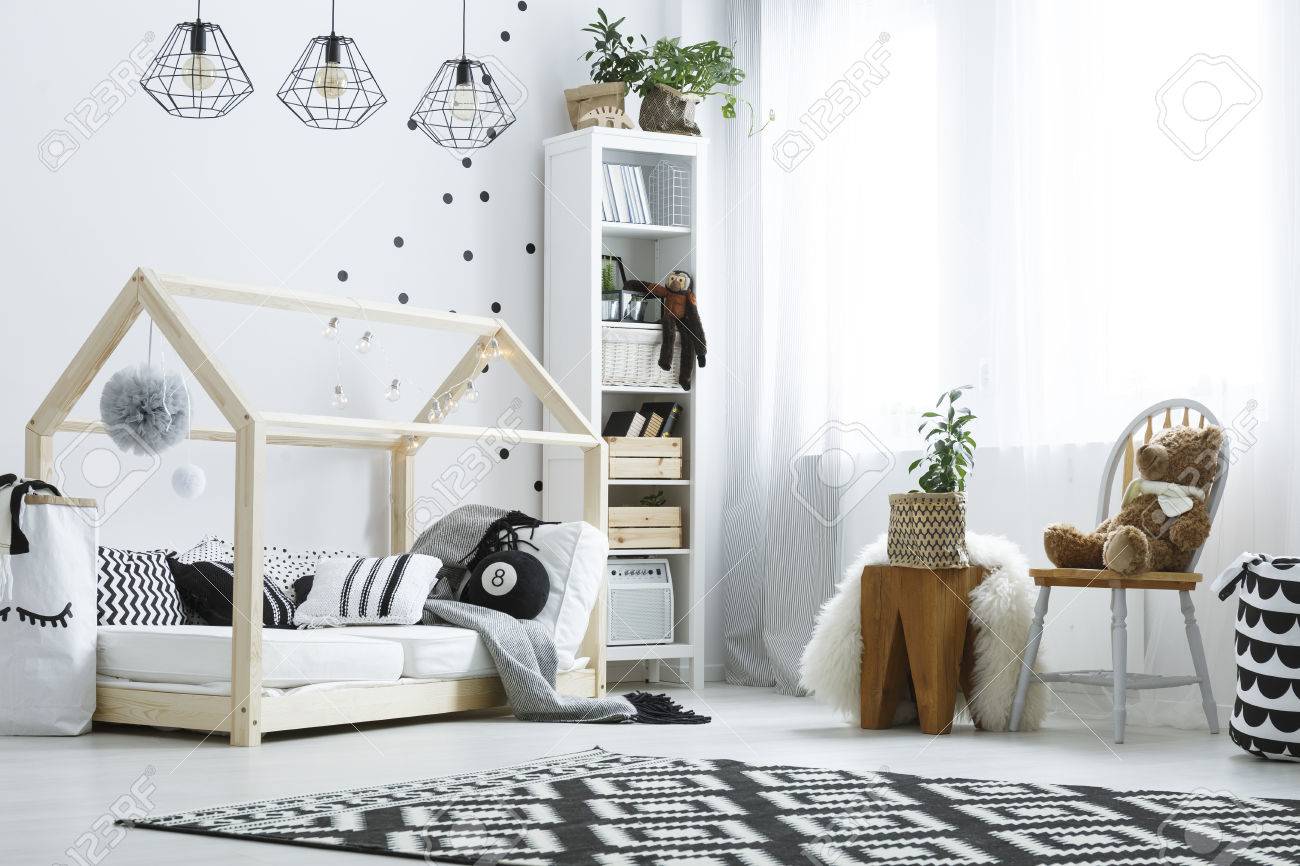 Kinderschlafzimmer mit weißer Wand, hölzernem Bett, Bücherschrank und Stuhl Kinderschlafzimmer mit weißer Wand, hölzernem Bett, Bücherschrank und Stuhl