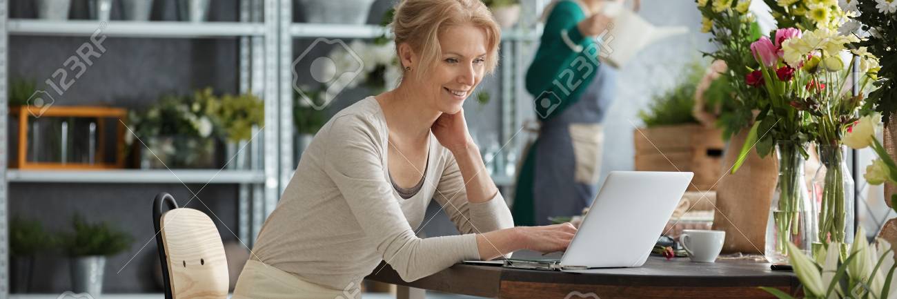 Young blonde woman with laptop and flowers on the desk - 77982172 Young blonde woman with laptop and flowers on the desk - 77982172