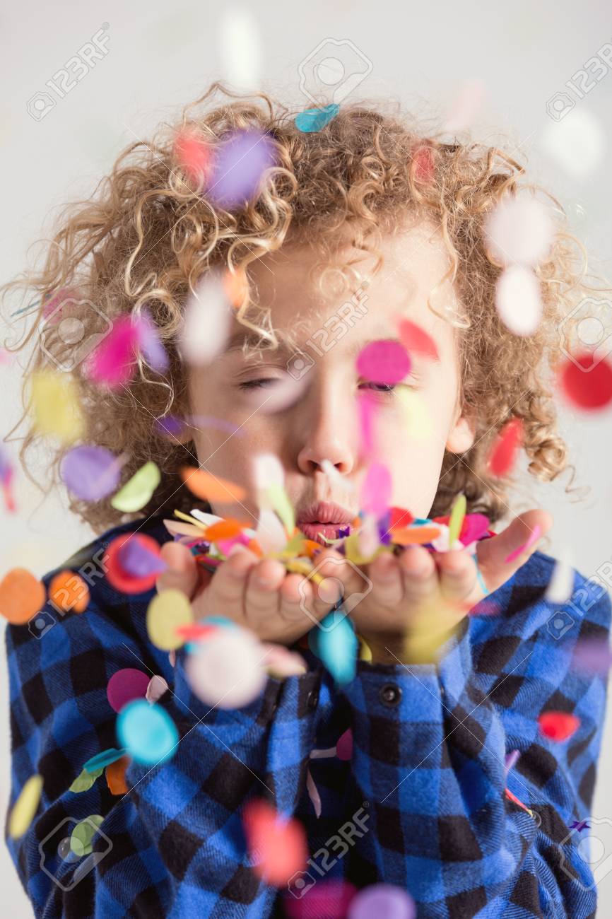 カラフルな紙吹雪を吹いて巻き毛の甘いの若い男の子 の写真素材 画像素材 Image
