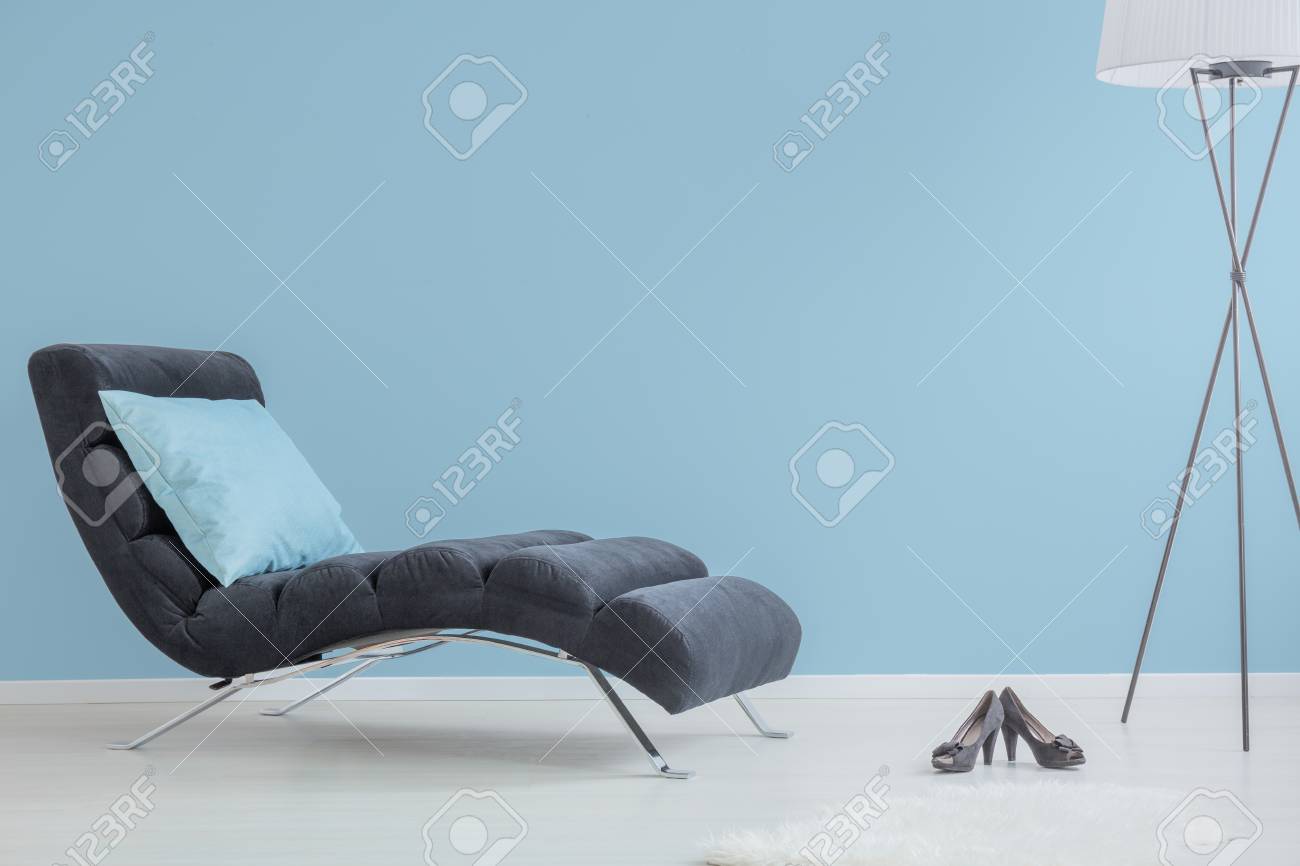 Salon élégant avec chaise longue, oreiller bleu, chaussures noires et lampe design Salon élégant avec chaise longue, oreiller bleu, chaussures noires et lampe design