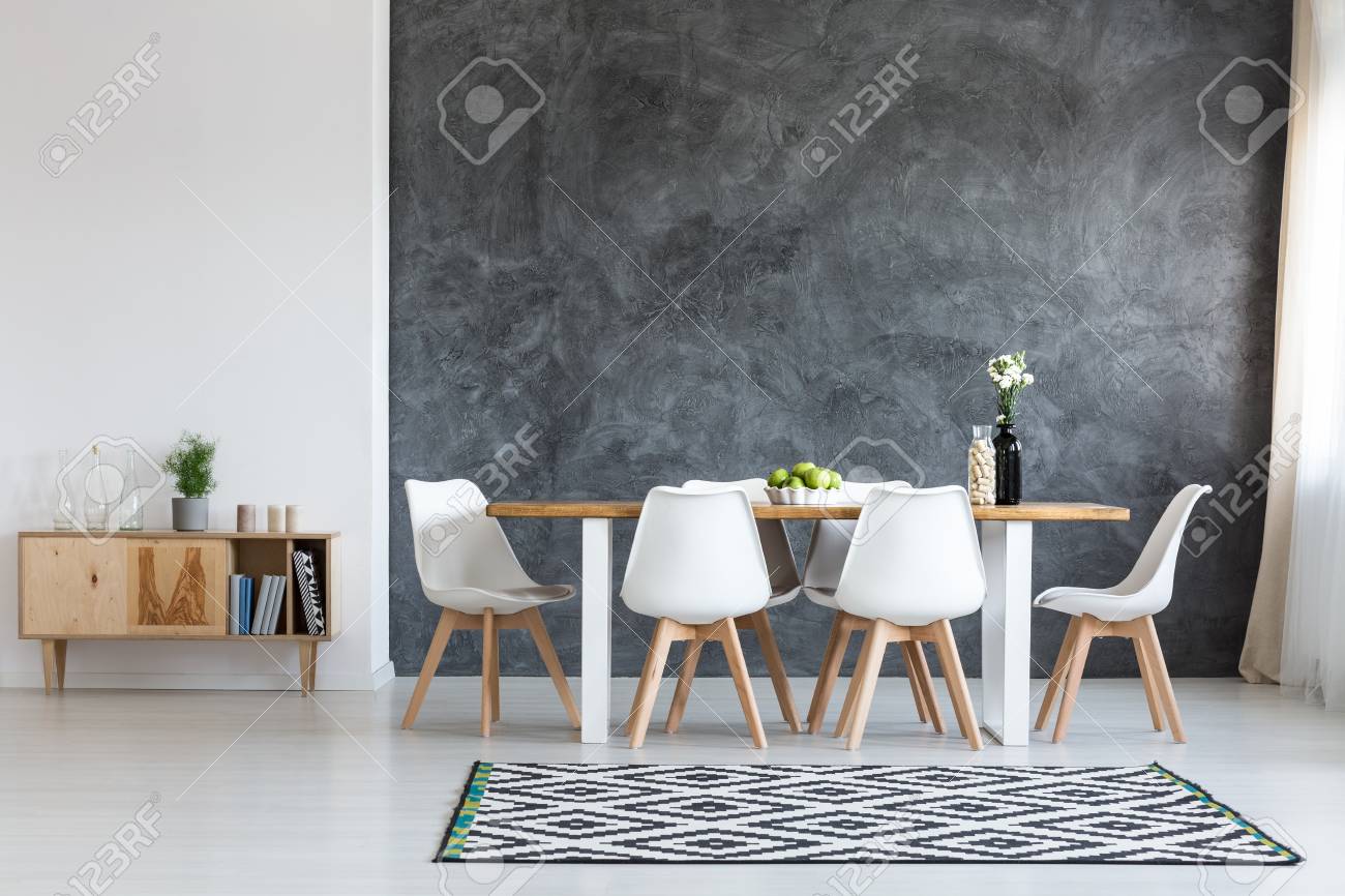 white flowers in black vase next to glass container with wine
