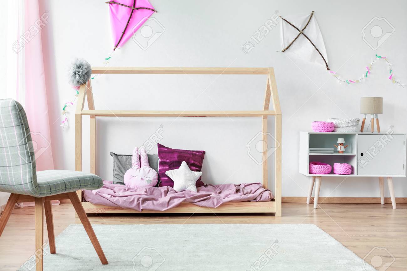 Grey Chair On White Carpet In Cozy Bedroom With Cute Pillows