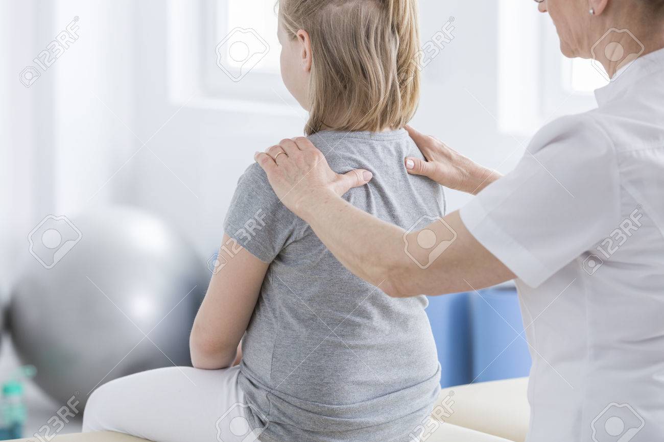 Physiotherapist massaging a girl with spine deformity during session in rehabilitation room - 87171314 Physiotherapist massaging a girl with spine deformity during session in rehabilitation room - 87171314