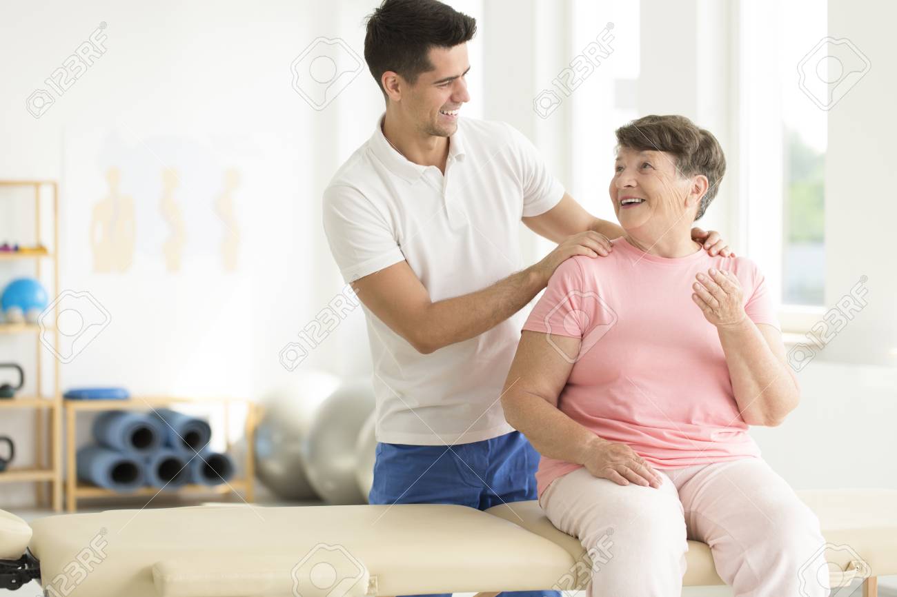Physiotherapist performing a rehabilitation session with his senior ward - 87560706 Physiotherapist performing a rehabilitation session with his senior ward - 87560706