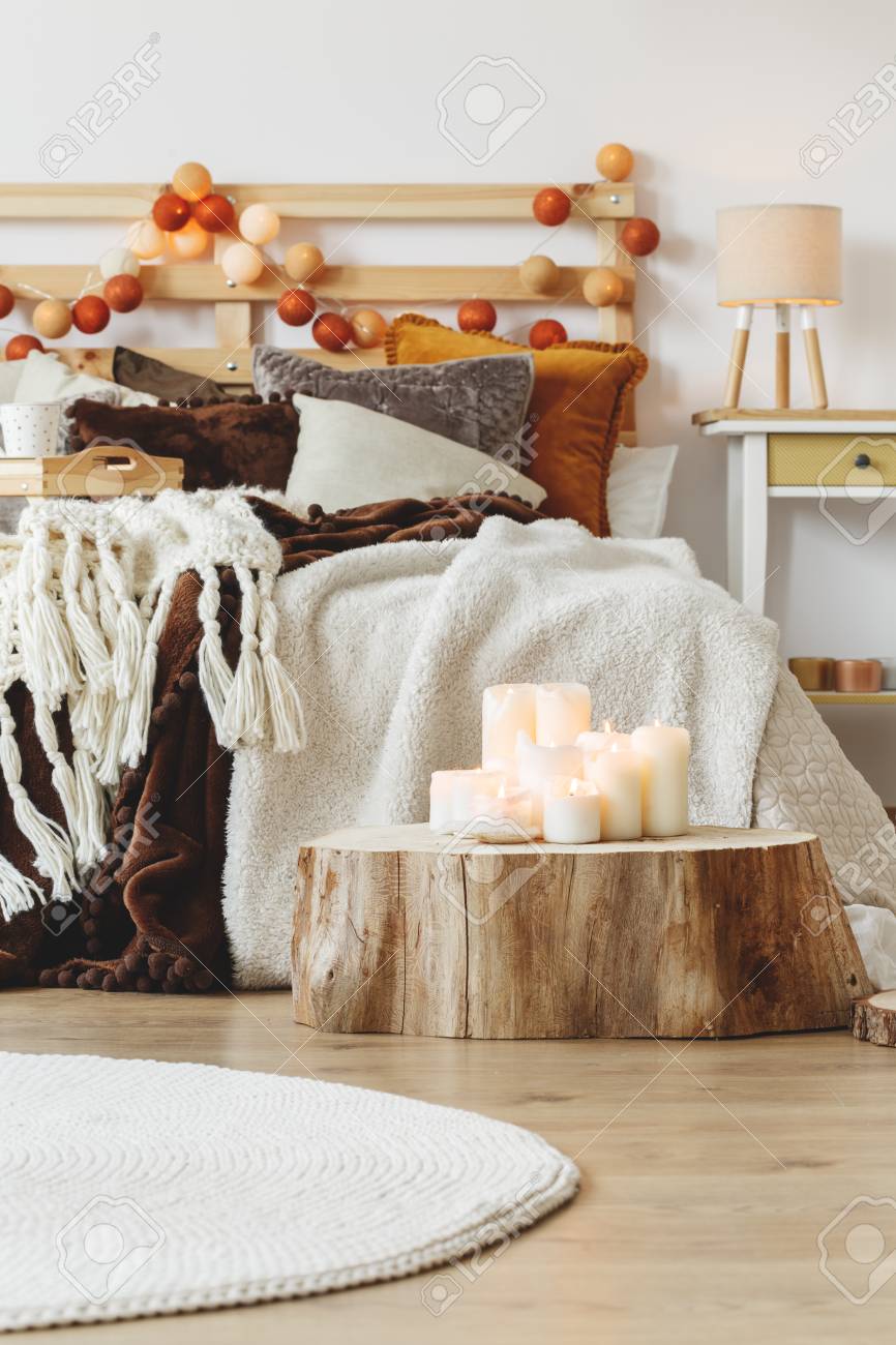 たくさんのキャンドルのスタイリッシュな寝室のベッドの横にある木の幹の上に立って の写真素材 画像素材 Image