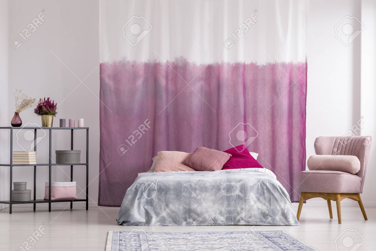 Pink Armchair Next To King Size Bed With Patterned Pillows Against