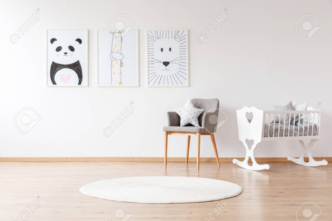 Grey chair with pillow and white round rug near white crib in baby's room with animal posters on the wall - 97990551 Grey chair with pillow and white round rug near white crib in baby's room with animal posters on the wall - 97990551