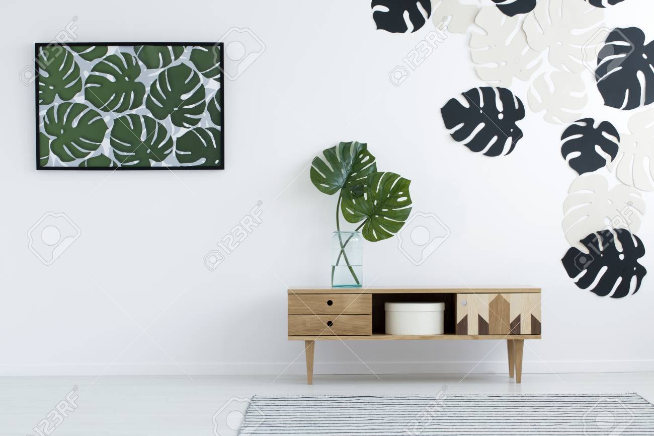 Wooden Cupboard With Monstera Leaves In Glass Vase Against White
