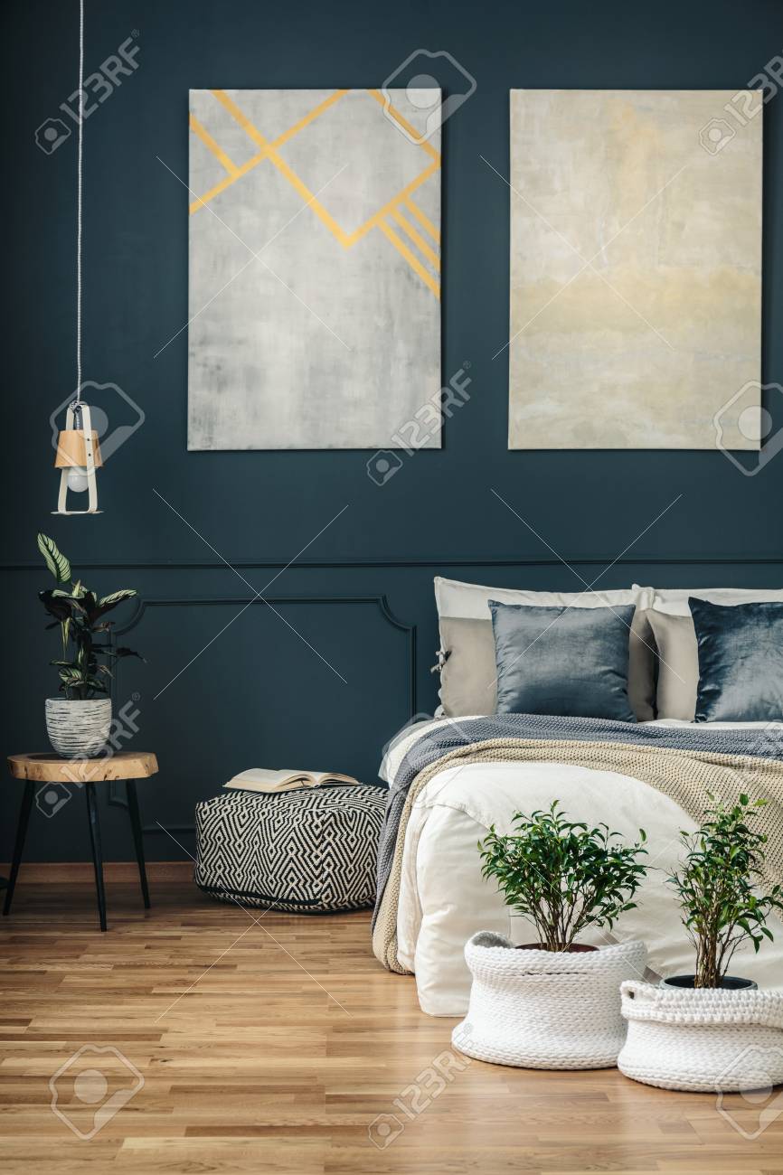 モダンアートと木製パネルを備えたダークなネイビーブルーのベッドルームインテリアの居心地の良いベッドの前の糸のバスケットに鉢植えの植物 の写真素材 画像素材 Image モダンアートと木製パネルを備えたダークなネイビーブルーのベッドルームインテリアの居心地の良いベッドの前の糸のバスケットに鉢植えの植物 の写真素材 画像素材 Image
