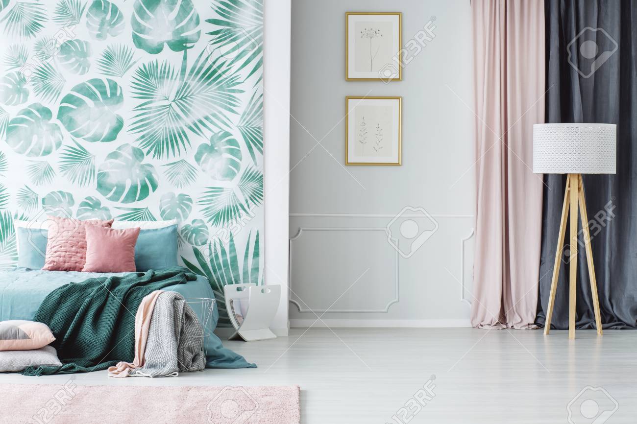 木製の三脚フロアランプと 居心地の良い淡い緑とピンクのベッドルームインテリアに枕と毛布付きの大きなベッド の写真素材 画像素材 Image