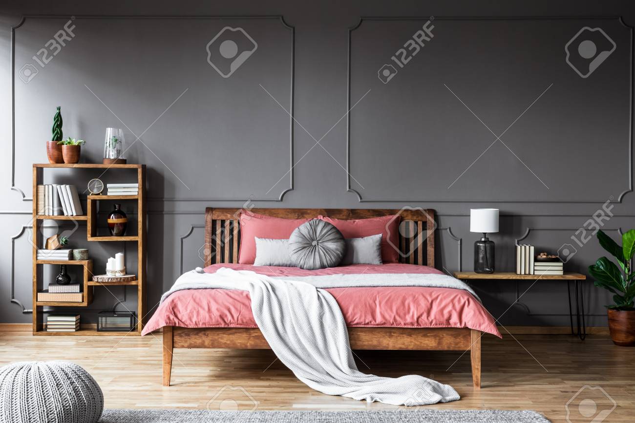 A Large Bed In A Spacious Dark Bedroom Standing Between A Shelf