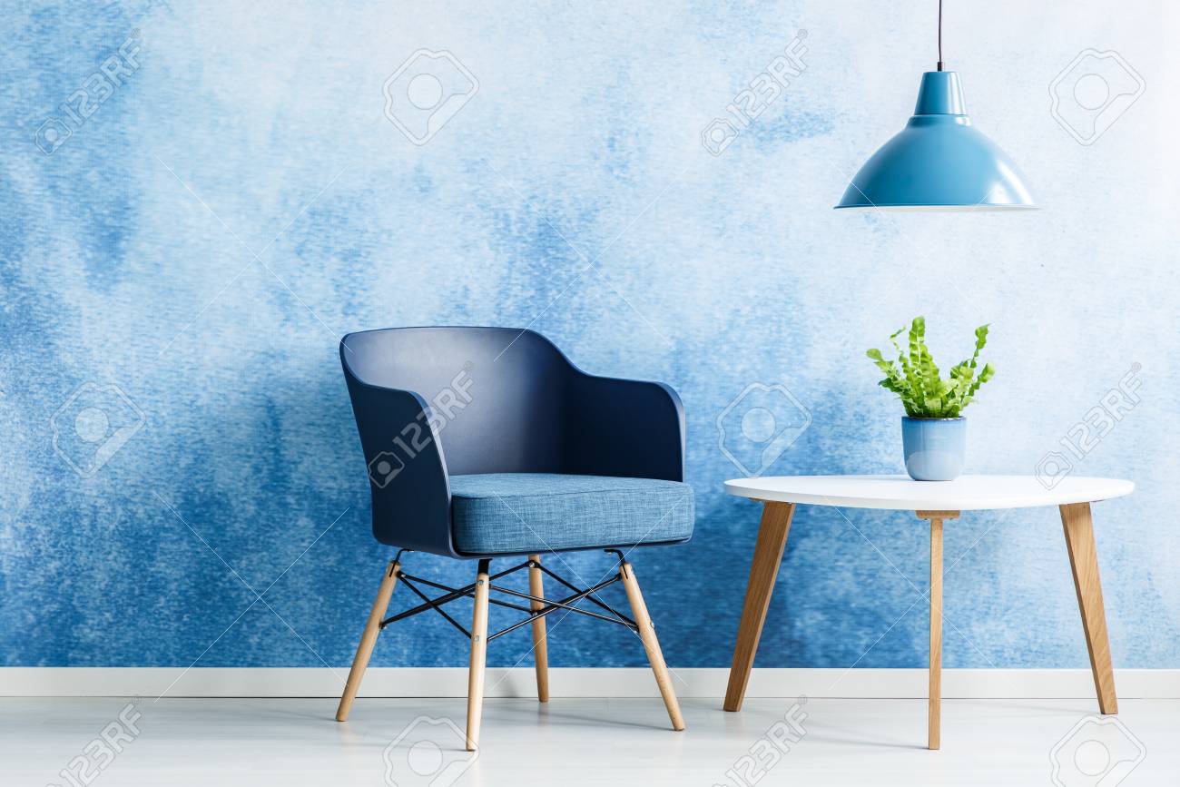navy blue armchair ottoman lamp above white table with plant next to navy blue armchair in simple living room interior above white table with plant next to navy blue armchair stock navy blue armchair ottoman lamp above white table with plant next to navy blue armchair in simple living room interior above white table with plant next to navy blue armchair stock