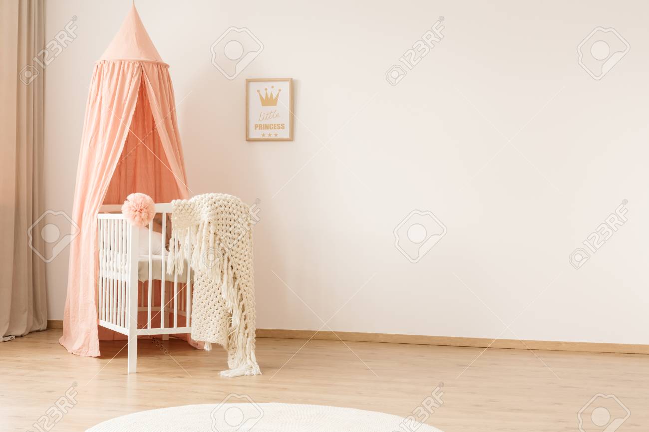 White woolen blanket and pastel pink pompom placed on a wooden crib with canopy in bright baby room interior with poster on the wall - 101692933 White woolen blanket and pastel pink pompom placed on a wooden crib with canopy in bright baby room interior with poster on the wall - 101692933