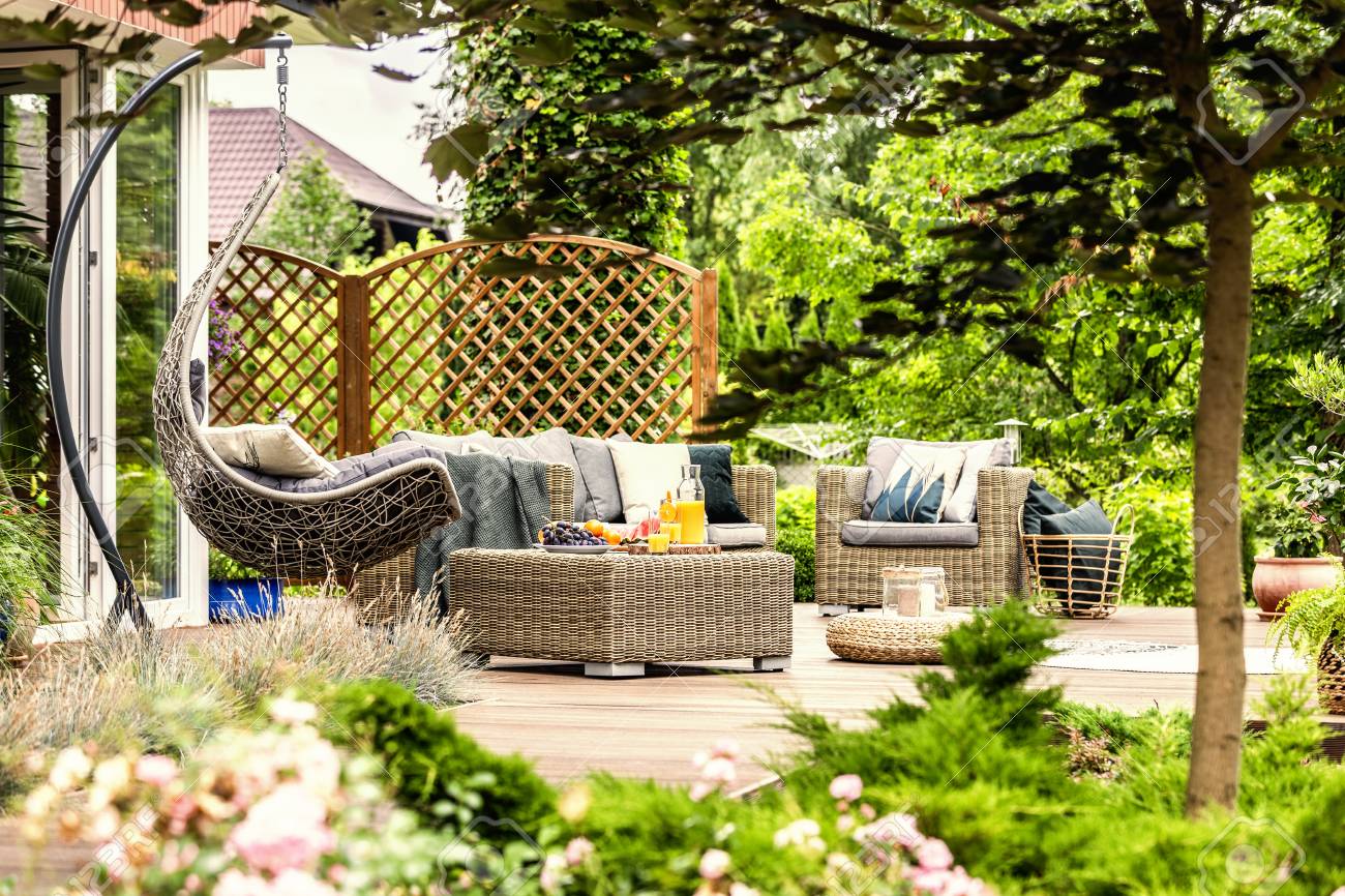 Rattan Garden Furniture And Hanging Chair On Wooden Terrace Of