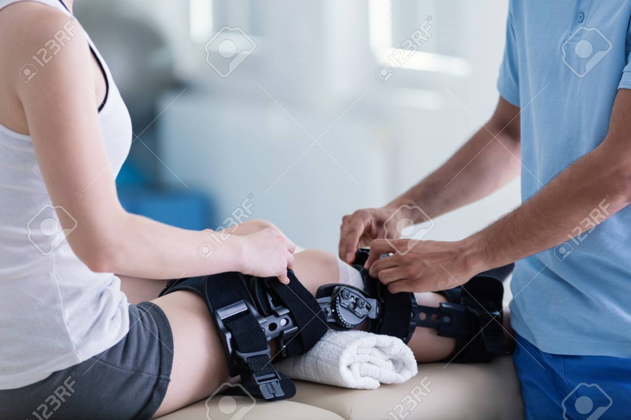 Close-up on person with stiffener on broken leg during rehabilitation with physiotherapist - 108108395 Close-up on person with stiffener on broken leg during rehabilitation with physiotherapist - 108108395