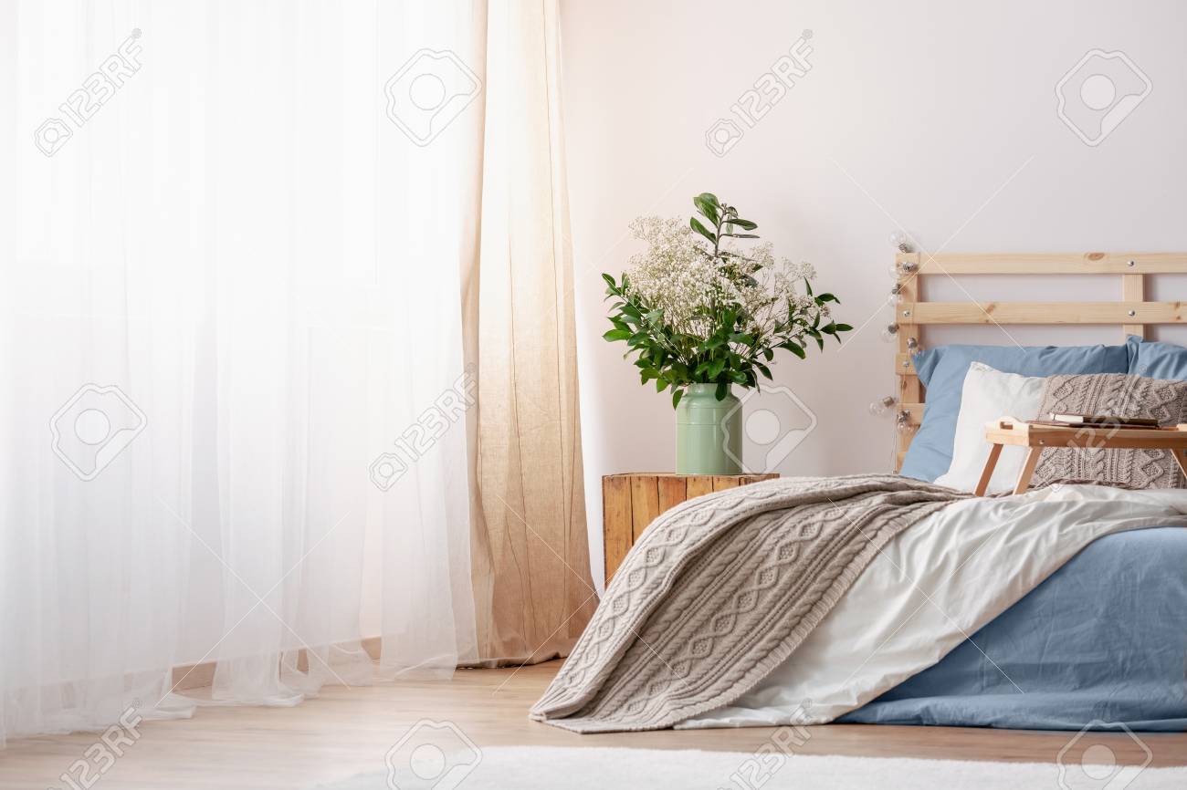 table next to bed cheap flowers on wooden table next to bed with blue and grey sheets in bright bedroom interior on wooden table next to bed with blue and grey sheets table next to bed cheap flowers on wooden table next to bed with blue and grey sheets in bright bedroom interior on wooden table next to bed with blue and grey sheets