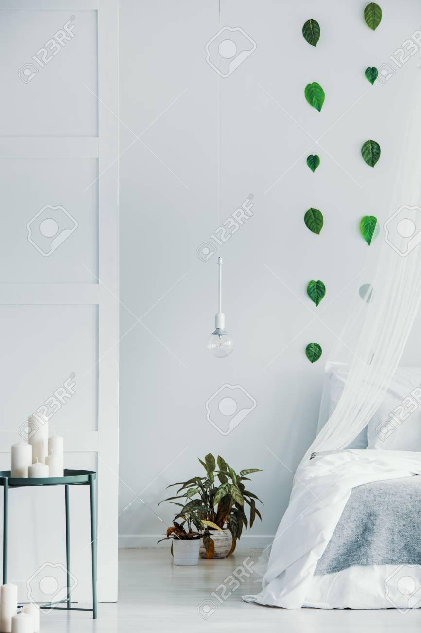 Light Bulb Above Plants In Post On The Floor Of Bright Bedroom