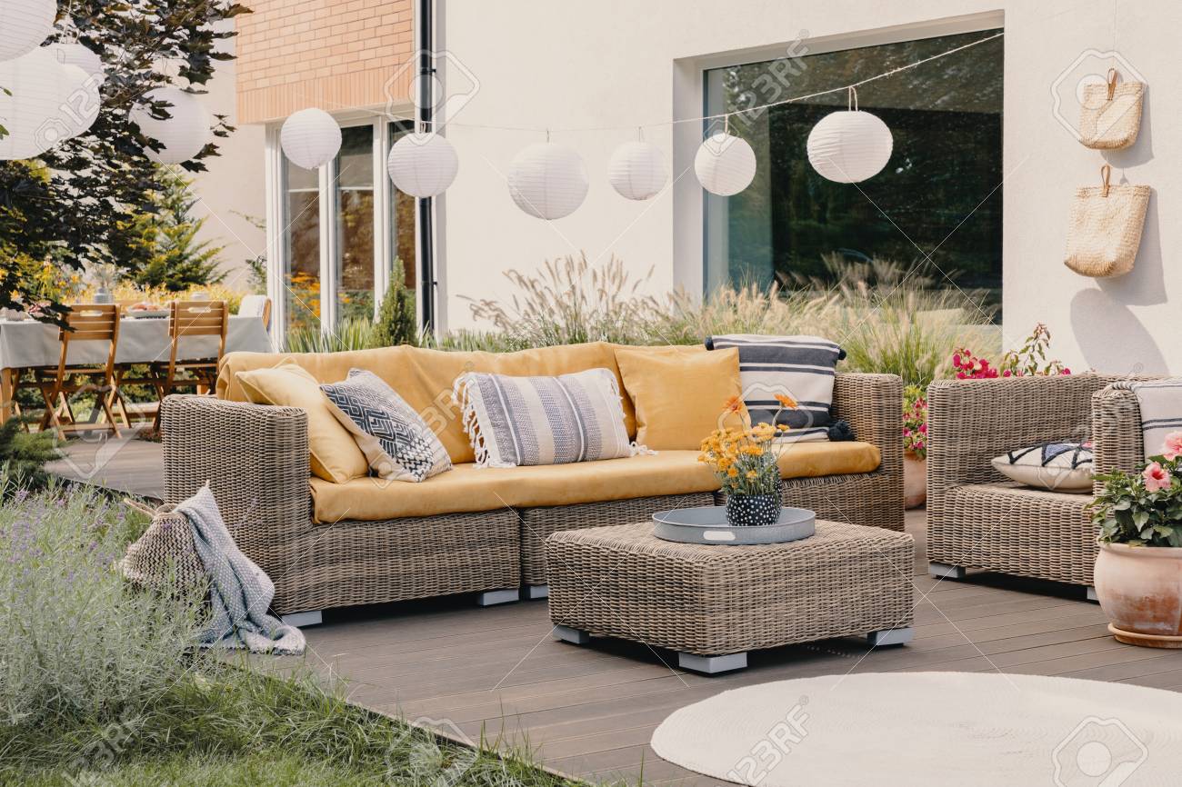 Real photo of a rattan garden furniture set with lamps and table in the background - 122007191 Real photo of a rattan garden furniture set with lamps and table in the background - 122007191