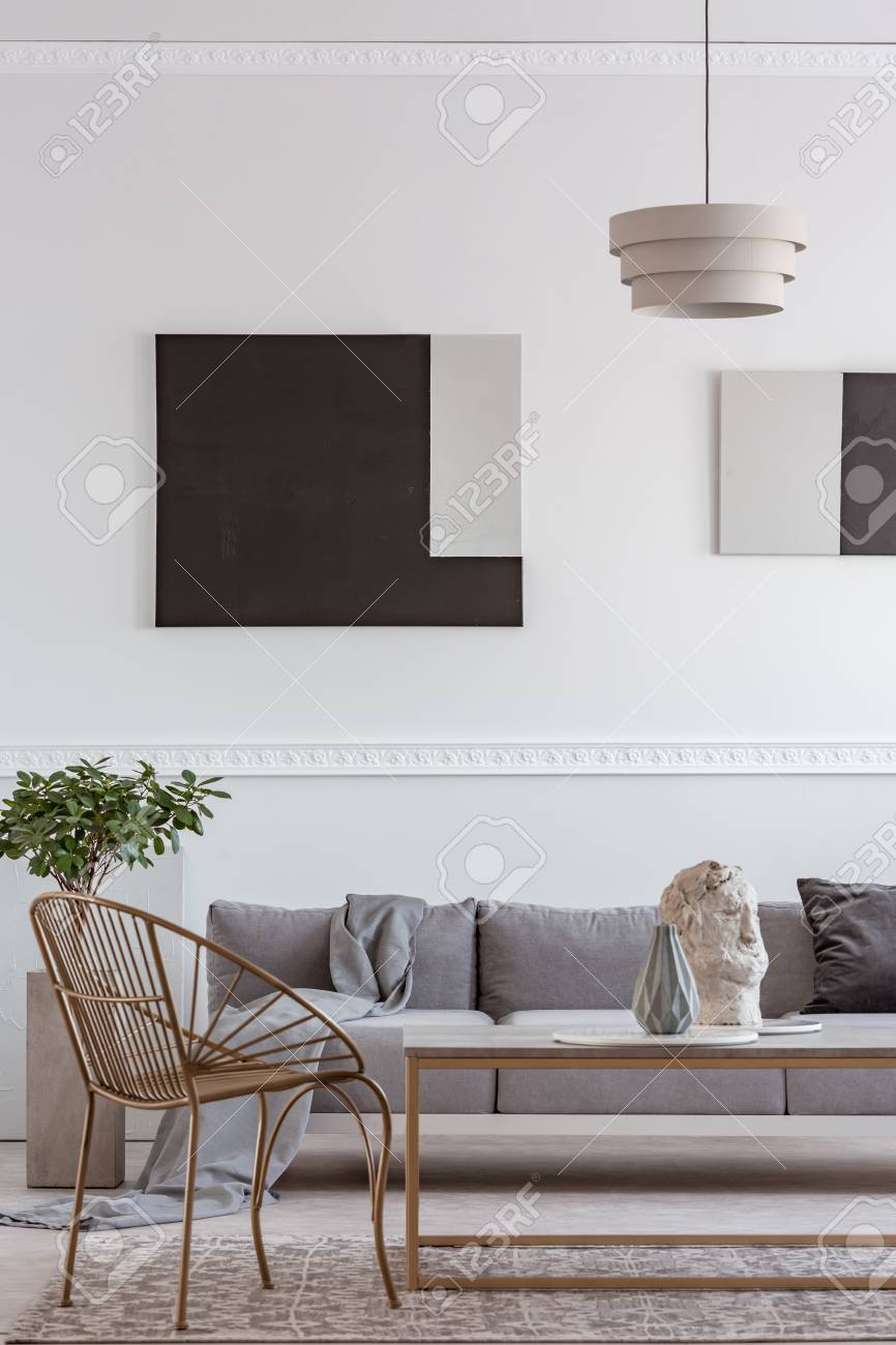 Stylish golden chair next to coffee table with vase in front of grey couch - 123114416 Stylish golden chair next to coffee table with vase in front of grey couch - 123114416