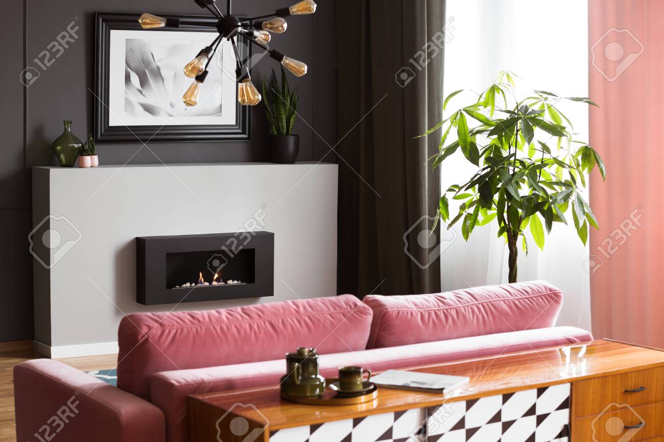 Antique Wooden Dresser Behind A Powder Pink Velvet Sofa In