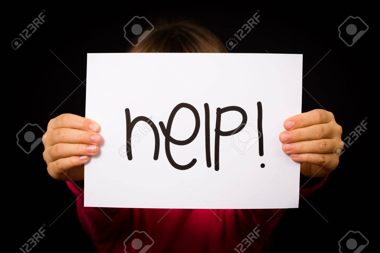 studio shot of child holding a help sign made of white paper stock helpsign