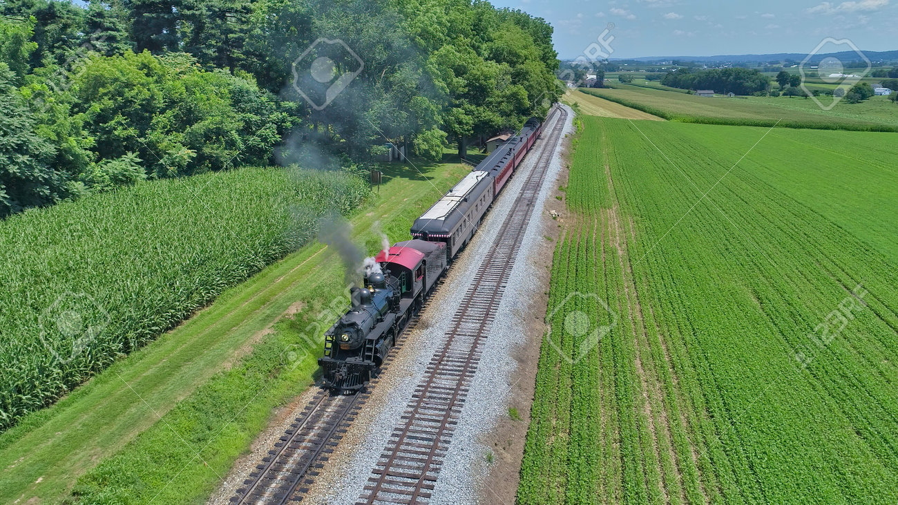 Aerial View of a Restored Antique Steam Engine and Passenger Cars Steaming Up at a Small Rail Road Station on a Summer Day - 162633880 Aerial View of a Restored Antique Steam Engine and Passenger Cars Steaming Up at a Small Rail Road Station on a Summer Day - 162633880
