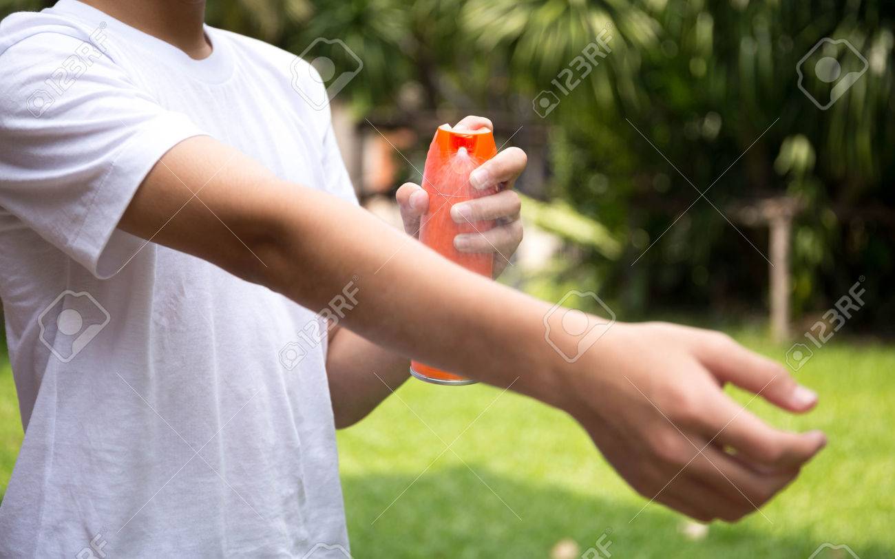 Young boy spraying insect repellents on skin in the garden with spray bottle - 68638253 Young boy spraying insect repellents on skin in the garden with spray bottle - 68638253