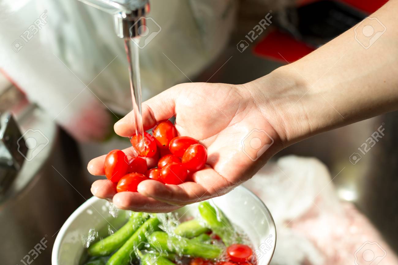 Hands washing fresh cherry tomatoes in running water in kitchen sink - 85888897 Hands washing fresh cherry tomatoes in running water in kitchen sink - 85888897