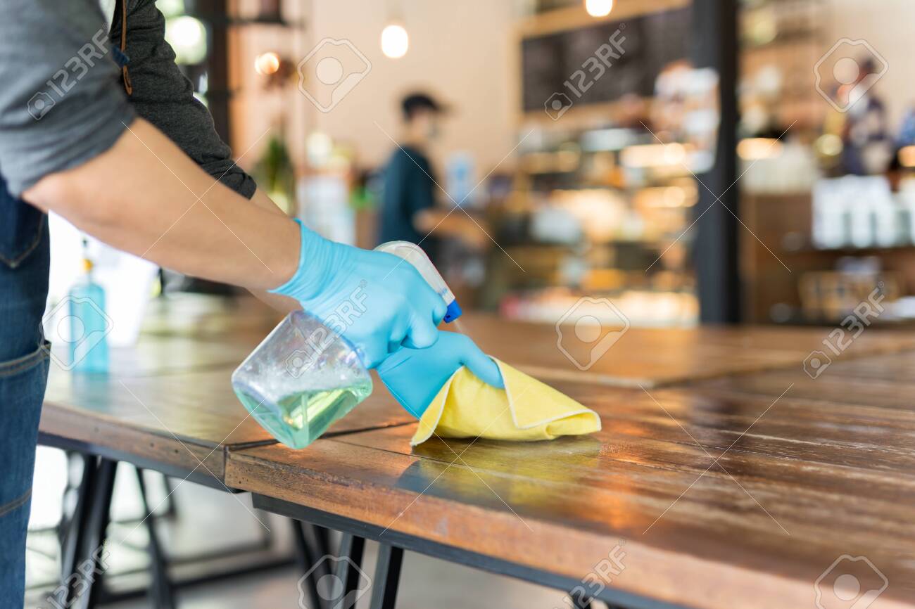 Waiter cleaning the table with disinfectant spray and microfiber cloth in cafe. - 143489088 Waiter cleaning the table with disinfectant spray and microfiber cloth in cafe. - 143489088
