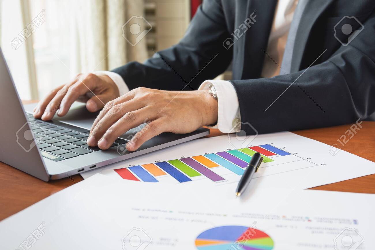 Businessman working on laptop with graph stock chart on table. - 144589128 Businessman working on laptop with graph stock chart on table. - 144589128