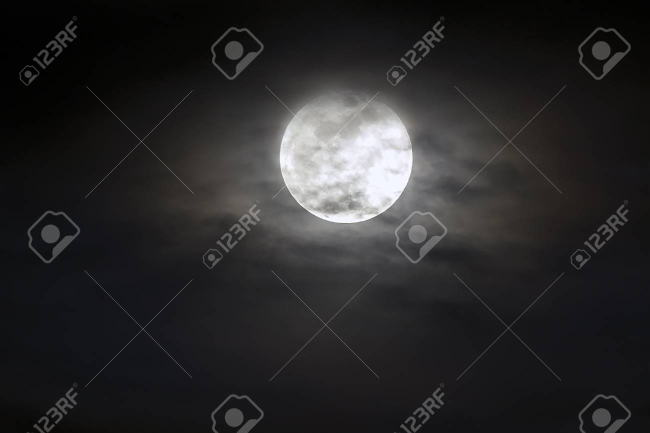 Big silver glowing Moon close-up on dark blue sky with scattered clouds. - 96084646 Big silver glowing Moon close-up on dark blue sky with scattered clouds. - 96084646