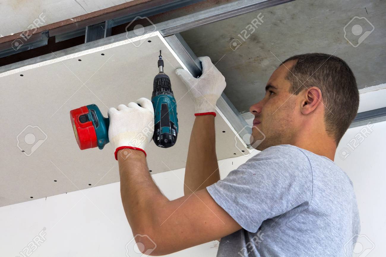 Construction Worker Assemble A Suspended Ceiling With Drywall