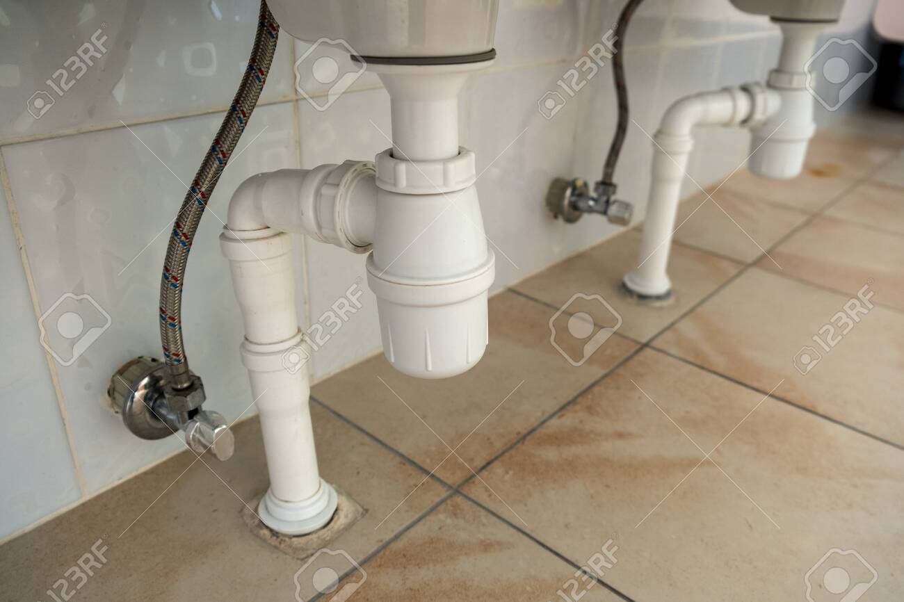 Close Up Of White Plastic Pipe Drain Under Washing Sink In Bathroom Stock Photo