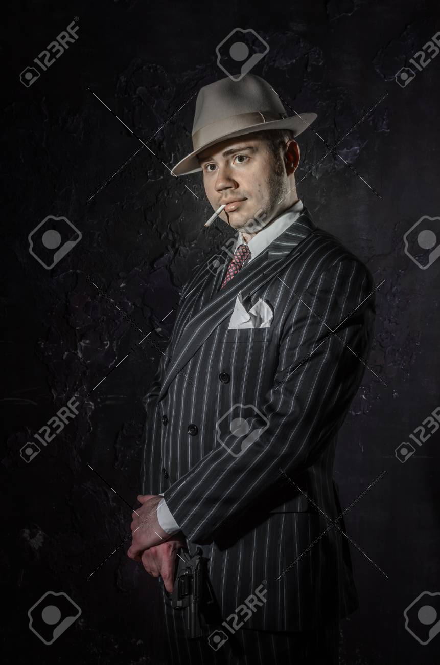 古いファッション帽子の私立探偵は タバコを吸います ギャングは マフィアのようでいてカメラ側 彼は暴徒のジャケットを着ています 黒と白で警察犯罪シーン スタジオ撮影します の写真素材 画像素材 Image