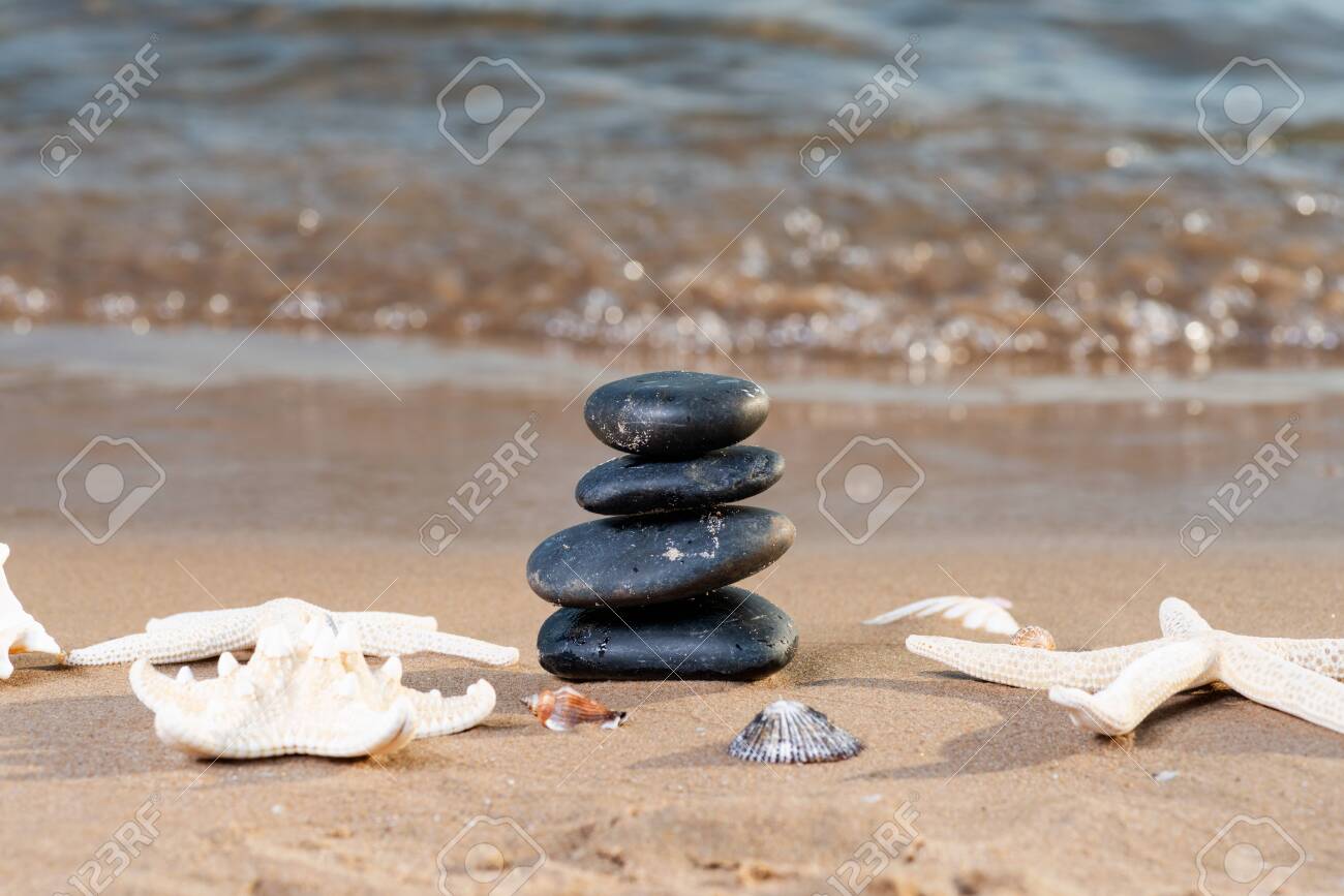 Spa composition - stacked Basalt Stones, Seashells and Sea Stars on the beach at sunrise in front of the ocean. Wellness, Balance and Relax concept. - 128873586 Spa composition - stacked Basalt Stones, Seashells and Sea Stars on the beach at sunrise in front of the ocean. Wellness, Balance and Relax concept. - 128873586