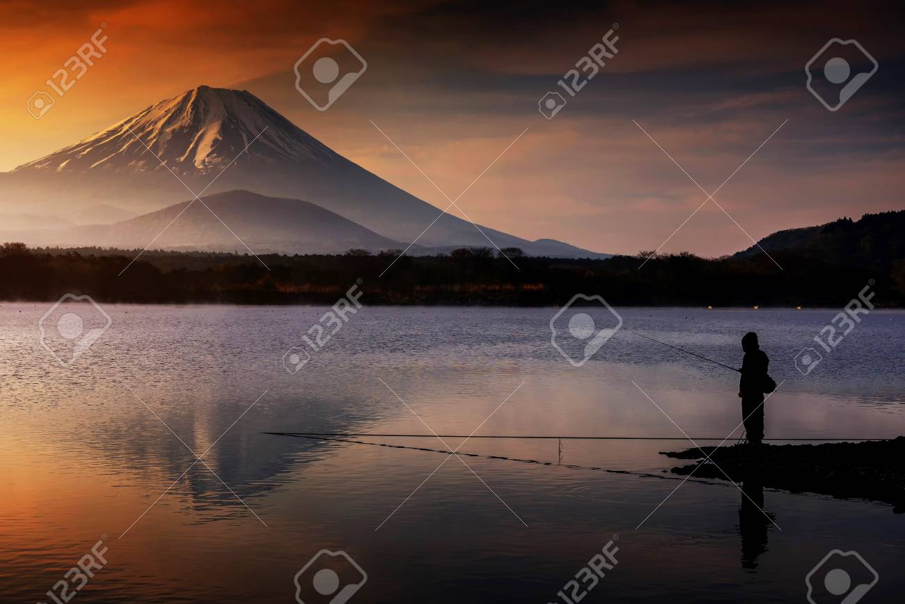 山梨県山梨の夜明けの日の出時に 富士山や富士山で水の反射と夕暮れの空を持つ正地湖で釣りをするシルエットマンの風景 の写真素材 画像素材 Image