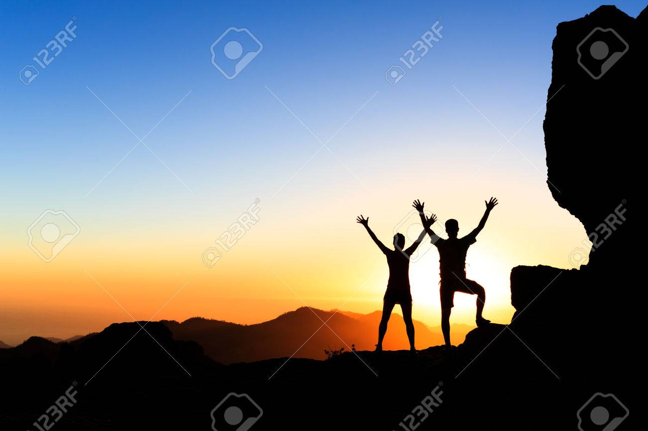 Couple hikers success in sunset mountains, accomplish with arms up outstretched. Young man and woman on rocky mountain range looking at beautiful inspirational landscape view, Gran Canaria Canary Islands. - 46613359 Couple hikers success in sunset mountains, accomplish with arms up outstretched. Young man and woman on rocky mountain range looking at beautiful inspirational landscape view, Gran Canaria Canary Islands. - 46613359