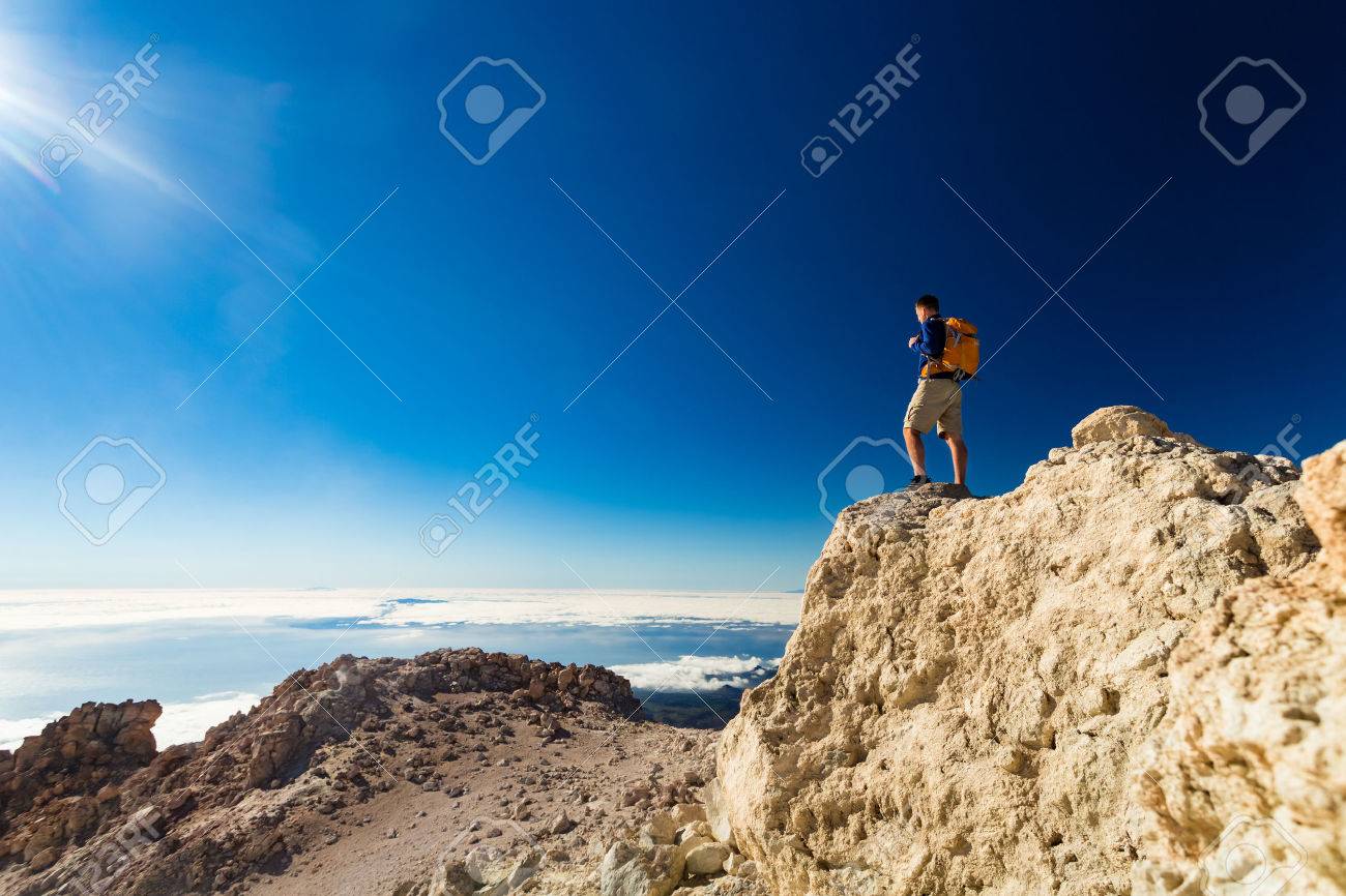 Man tourist hiker or trail runner looking at beautiful inspirational landscape in high mountains. Male runner with backpack, happiness and enjoying inspiring view on rocky top of mountain, Spain. - 57161617 Man tourist hiker or trail runner looking at beautiful inspirational landscape in high mountains. Male runner with backpack, happiness and enjoying inspiring view on rocky top of mountain, Spain. - 57161617